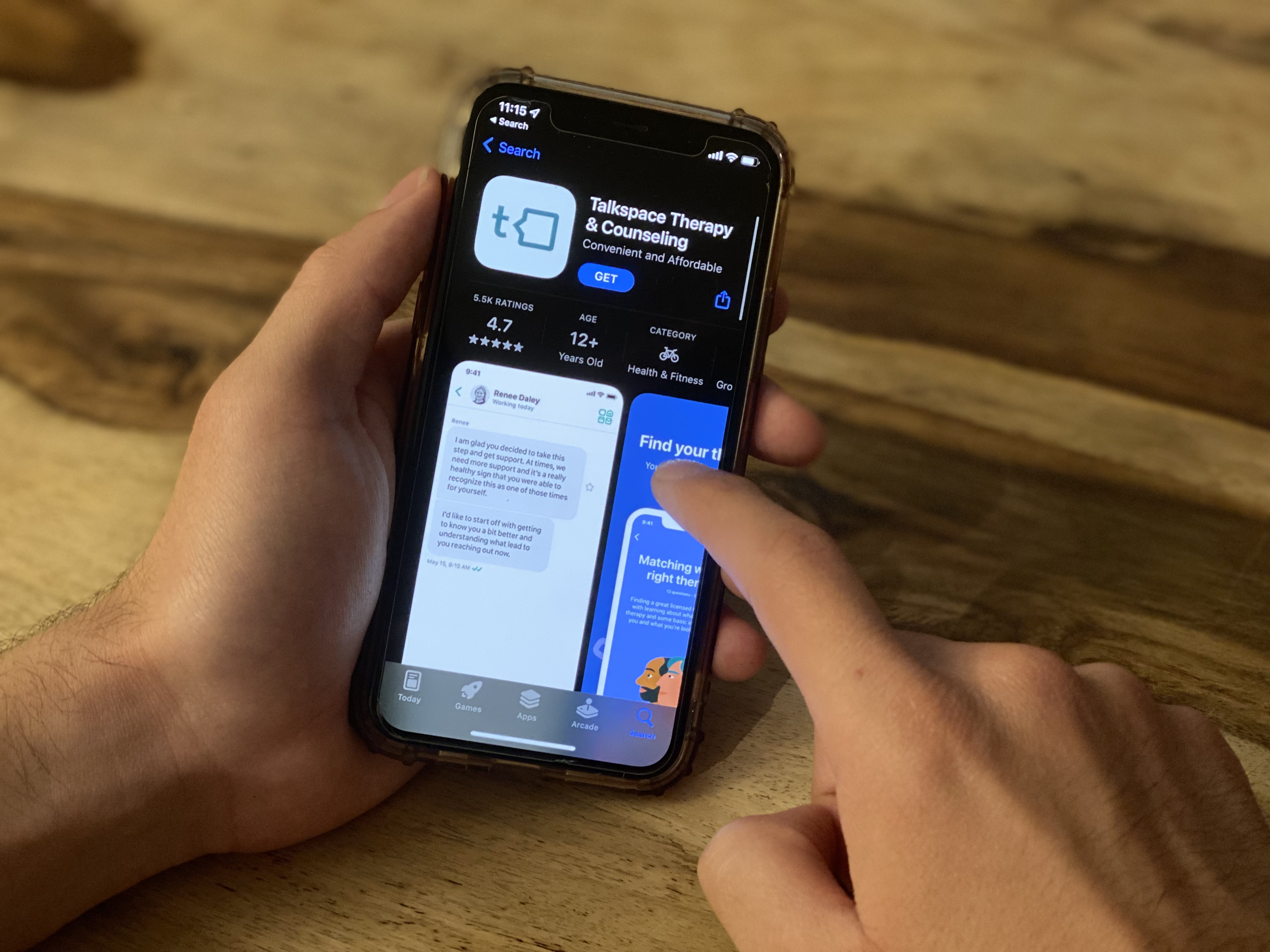 Hand holding iPhone looking at TalkSpace app in the Apple App Store.